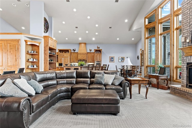 carpeted living room featuring plenty of natural light, a brick fireplace, and a high ceiling