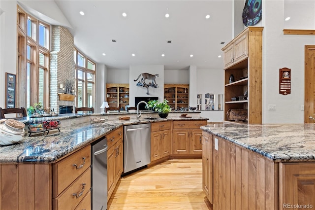 kitchen with stone counters, dishwasher, light hardwood / wood-style flooring, and a spacious island