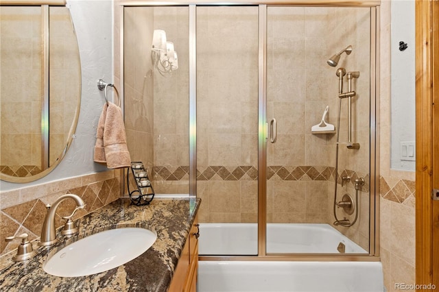 bathroom with shower / bath combination with glass door, vanity, tile walls, and backsplash