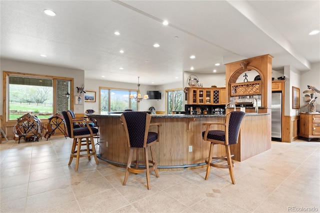 kitchen with a kitchen breakfast bar, stainless steel fridge, pendant lighting, a center island, and a chandelier