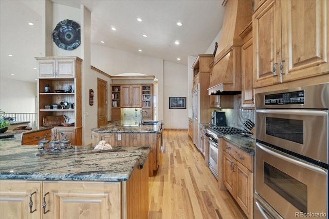 5881 Deer Meadow Trl, Golden, CO 80403 - kitchen with appliances with stainless steel finishes, an island with sink, light wood-type flooring, recessed lighting, and dark stone countertops