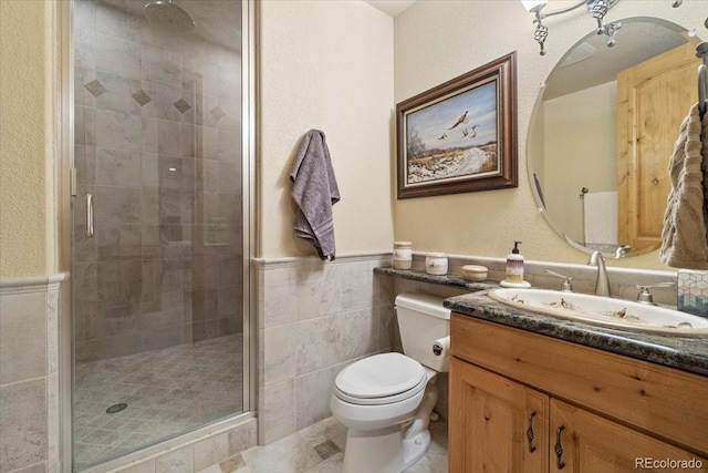 5881 Deer Meadow Trl, Golden, CO 80403 - bathroom with toilet, a stall shower, vanity, tile walls, and a wainscoted wall
