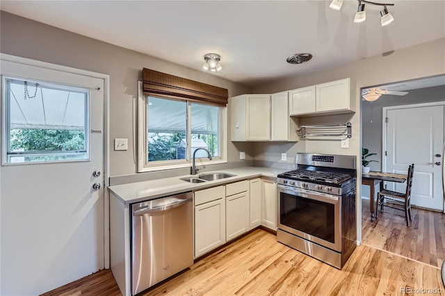 kitchen with sink, ceiling fan, light wood-type flooring, white cabinetry, and stainless steel appliances