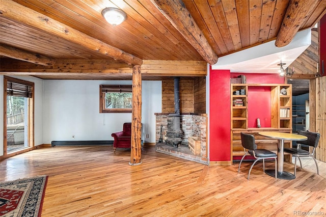 10419 Christopher Dr, Conifer, CO 80433 - living room with a wood stove, wood finished floors, wooden ceiling with exposed beams, and baseboards