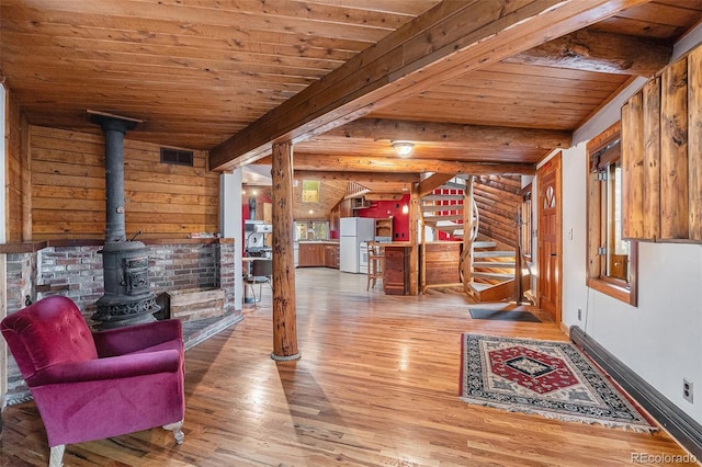 10419 Christopher Dr, Conifer, CO 80433 - living area featuring a wood stove, wood finished floors, wooden ceiling with exposed beams, log walls, and stairs