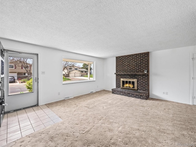 unfurnished living room featuring carpet flooring, a textured ceiling, visible vents, and a fireplace