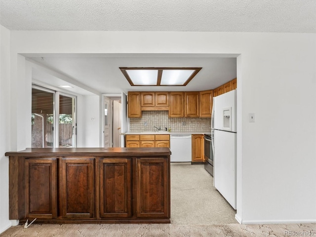 kitchen with a peninsula, light colored carpet, a sink, and white appliances
