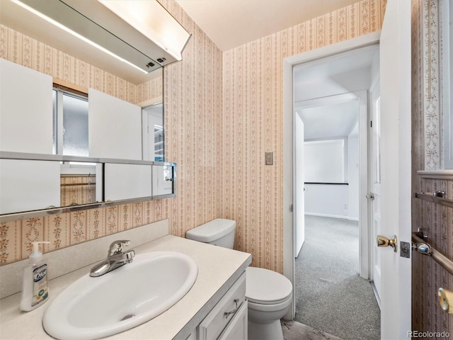 bathroom with wallpapered walls, toilet, and vanity