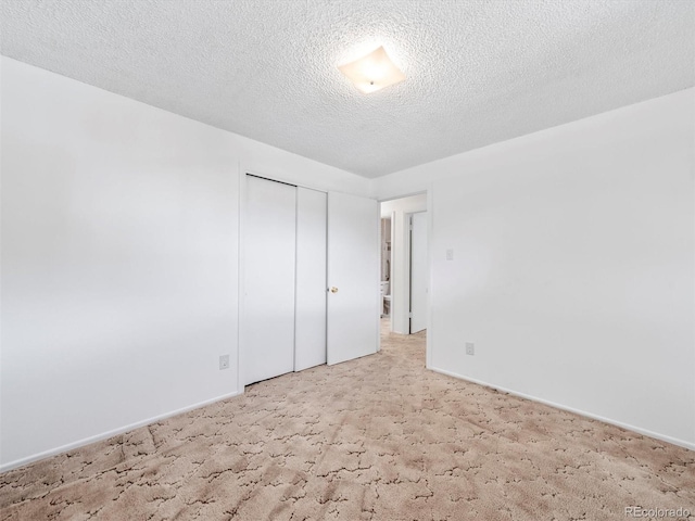 unfurnished bedroom featuring a textured ceiling, a closet, carpet flooring, and baseboards