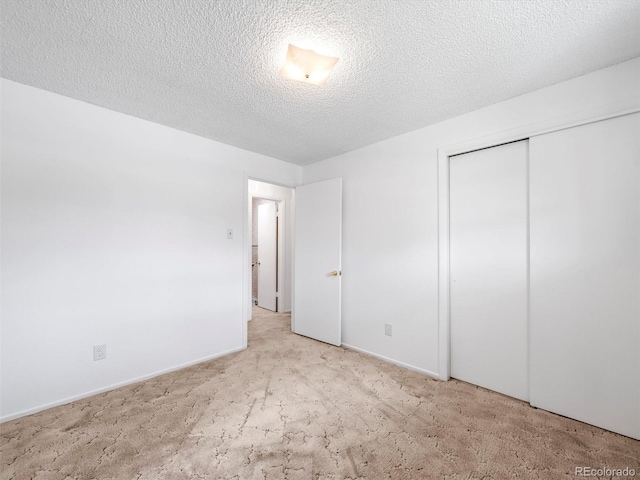unfurnished bedroom with baseboards, carpet flooring, a textured ceiling, and a closet
