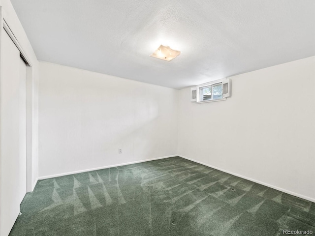 basement with baseboards, dark carpet, and a textured ceiling