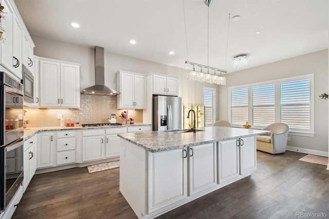 kitchen featuring a sink, white cabinets, wall chimney range hood, and stainless steel appliances