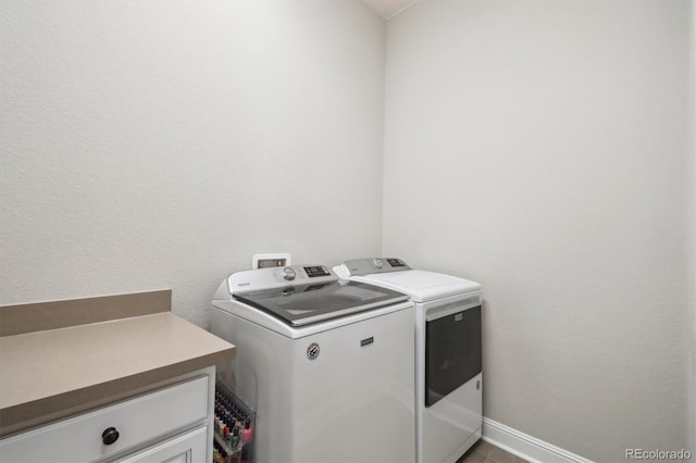 laundry room featuring baseboards, cabinet space, and washing machine and clothes dryer