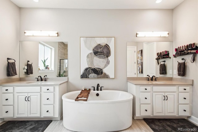 bathroom featuring a sink, a soaking tub, and two vanities