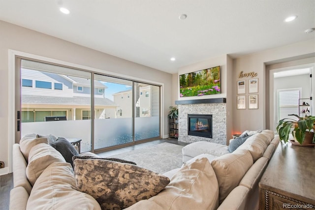living area with a stone fireplace, recessed lighting, and wood finished floors