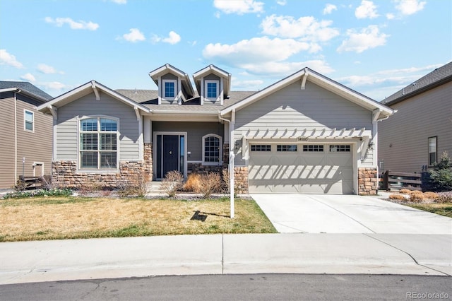 craftsman-style house featuring a garage, concrete driveway, a front lawn, and stone siding