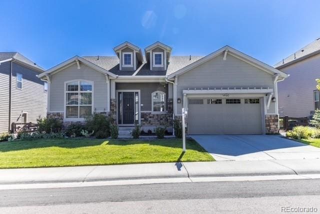 14160 Ivanhoe St, Thornton, CO 80602 - craftsman-style home with a garage, driveway, stone siding, and a front lawn