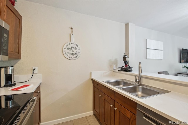 2880 S Locust St Unit 305N, Denver, CO 80222 - kitchen featuring a sink, stainless steel appliances, light countertops, and brown cabinetry