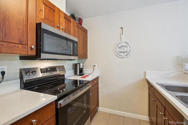 2880 S Locust St Unit 305N, Denver, CO 80222 - kitchen featuring stainless steel appliances, light countertops, brown cabinetry, and baseboards