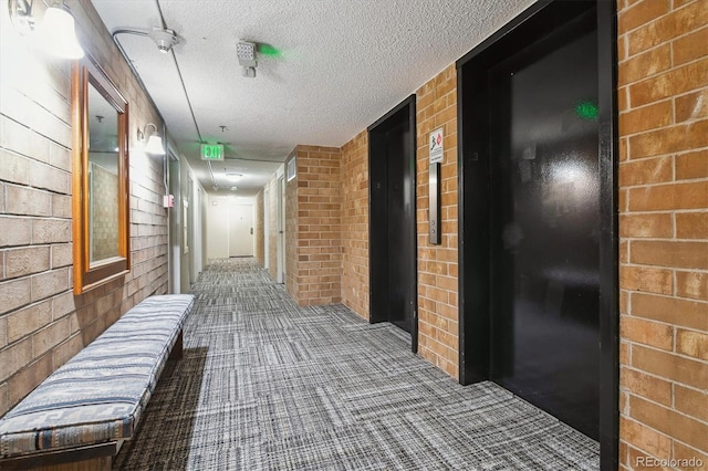 2880 S Locust St Unit 305N, Denver, CO 80222 - hallway with carpet, elevator, brick wall, and a textured ceiling