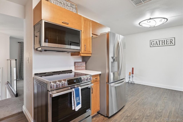 2843 S Otis St, Denver, CO 80227 - kitchen with stainless steel appliances, wood finished floors, light countertops, and brown cabinets