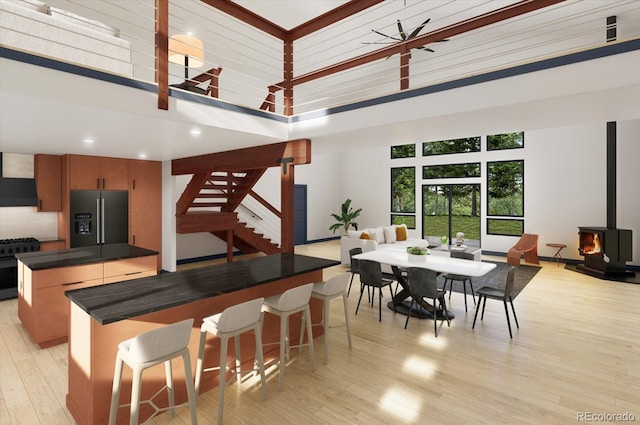 kitchen featuring black gas stove, a wood stove, a towering ceiling, a kitchen island, and refrigerator with ice dispenser