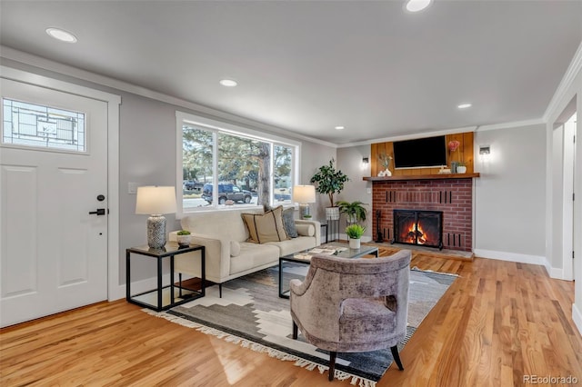 living room featuring baseboards, ornamental molding, a brick fireplace, and light wood-style floors