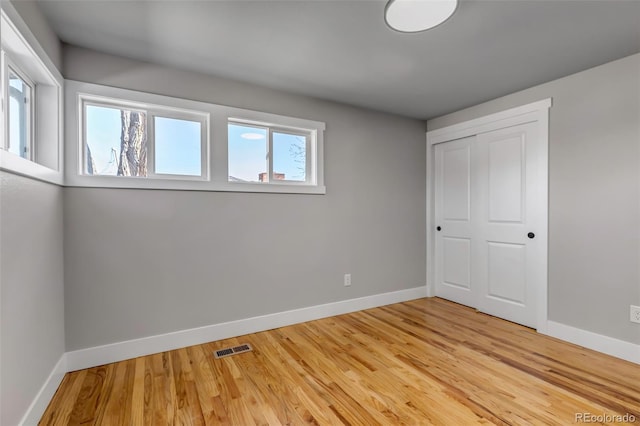 unfurnished bedroom featuring a closet, light wood-type flooring, visible vents, and baseboards