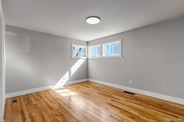 unfurnished room featuring visible vents, baseboards, and wood finished floors