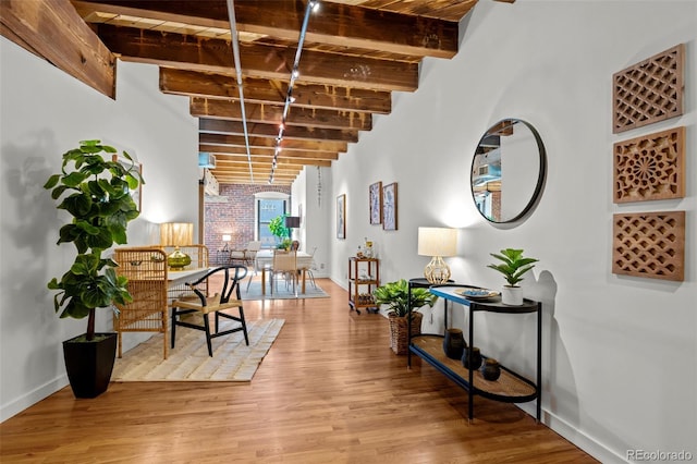 interior space with beamed ceiling, light wood-style flooring, and baseboards