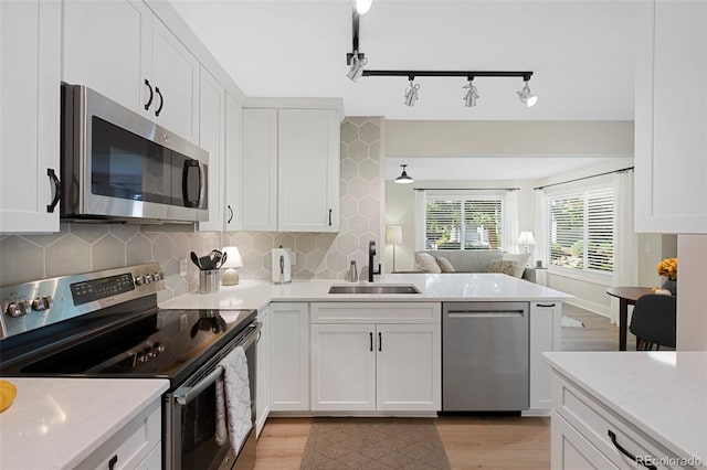 kitchen with appliances with stainless steel finishes, light hardwood / wood-style floors, white cabinetry, and sink