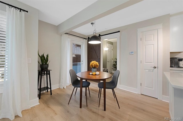 dining area featuring light wood-type flooring and a barn door