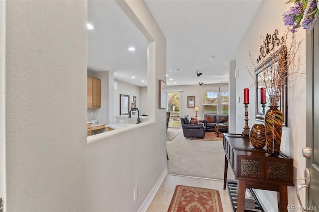 hallway featuring recessed lighting, baseboards, and a sink