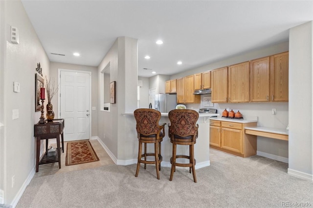 kitchen with freestanding refrigerator, a breakfast bar area, recessed lighting, light colored carpet, and under cabinet range hood