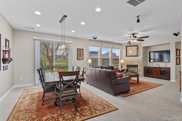 carpeted living area featuring a glass covered fireplace, plenty of natural light, ceiling fan, and visible vents