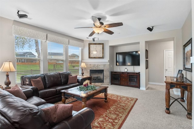 living room with a ceiling fan, baseboards, light colored carpet, and a tiled fireplace