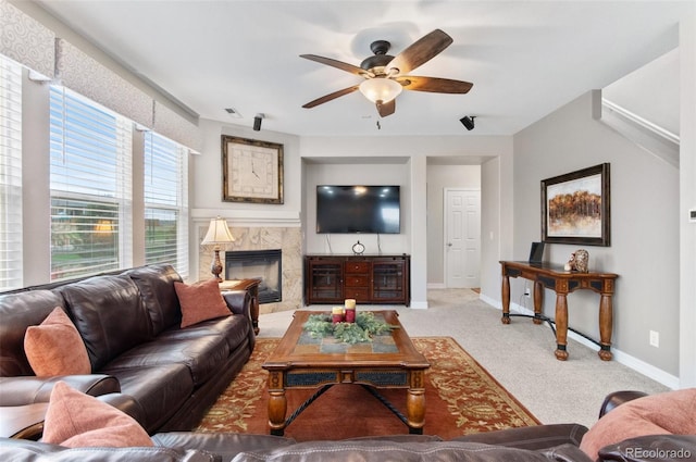 living area featuring ceiling fan, visible vents, baseboards, carpet flooring, and a premium fireplace