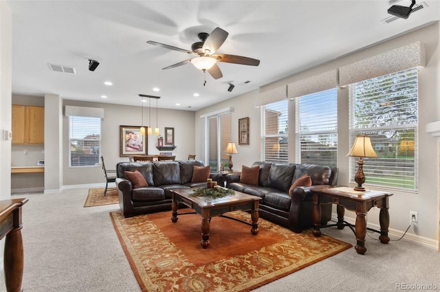 living area with baseboards, ceiling fan, light carpet, and visible vents