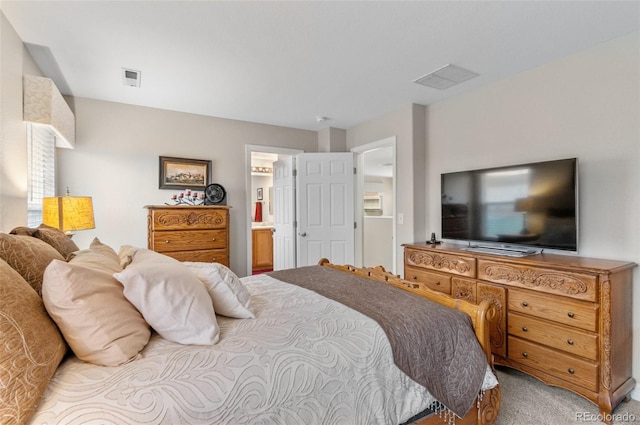 carpeted bedroom with visible vents and ensuite bath