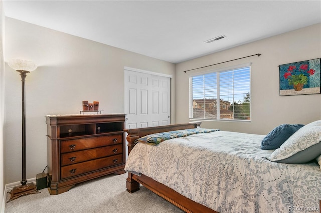 bedroom featuring baseboards, light carpet, a closet, and visible vents