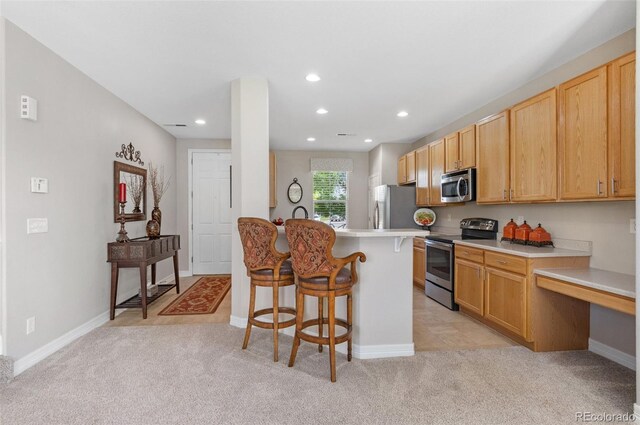 201 Shenandoah Way, Brighton, CO 80603 - kitchen with appliances with stainless steel finishes, a kitchen bar, light carpet, light countertops, and recessed lighting