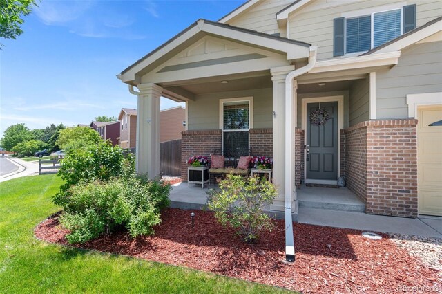 201 Shenandoah Way, Brighton, CO 80603 - view of exterior entry featuring brick siding, covered porch, and a lawn
