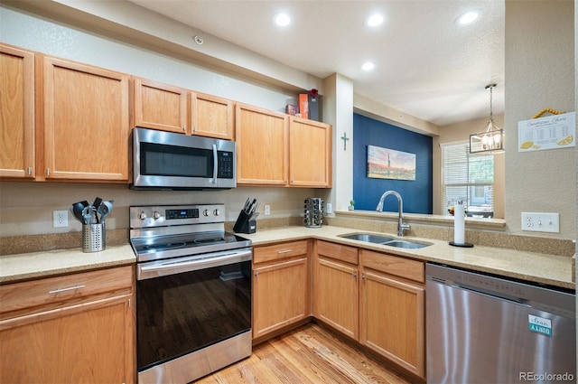 kitchen featuring light brown cabinets, sink, light wood-type flooring, stainless steel appliances, and a chandelier