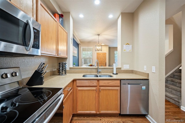 kitchen with sink, hanging light fixtures, dark wood-type flooring, stainless steel appliances, and a chandelier