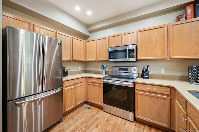 kitchen featuring light hardwood / wood-style flooring, light brown cabinets, and appliances with stainless steel finishes