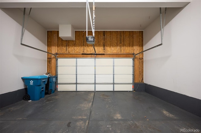 garage with a garage door opener and wood walls