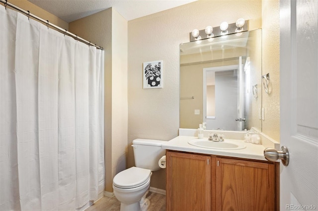 bathroom with vanity, toilet, and a textured ceiling