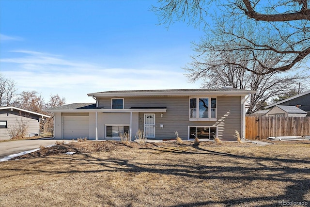 split foyer home with driveway, a garage, fence, and a front lawn