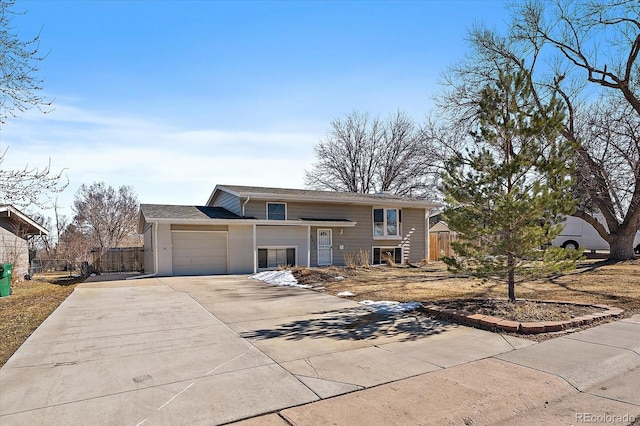 split foyer home featuring a garage, fence, and concrete driveway