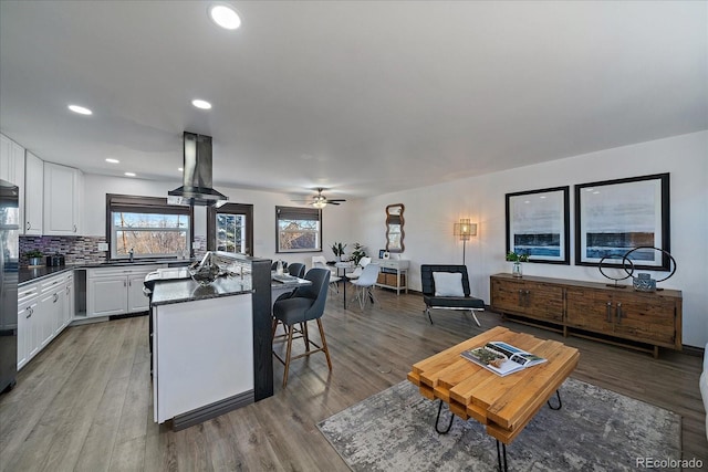 kitchen featuring dark countertops, light wood-style floors, island exhaust hood, and white cabinetry